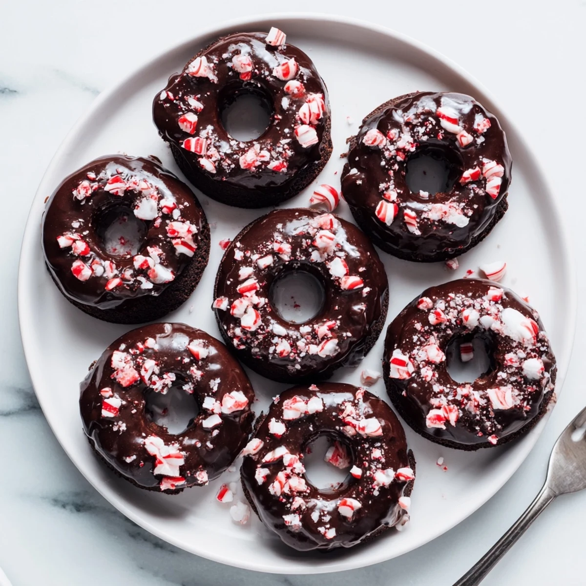 Soft chocolate peppermint mochi donuts topped with rich cocoa glaze and crushed candy cane pieces