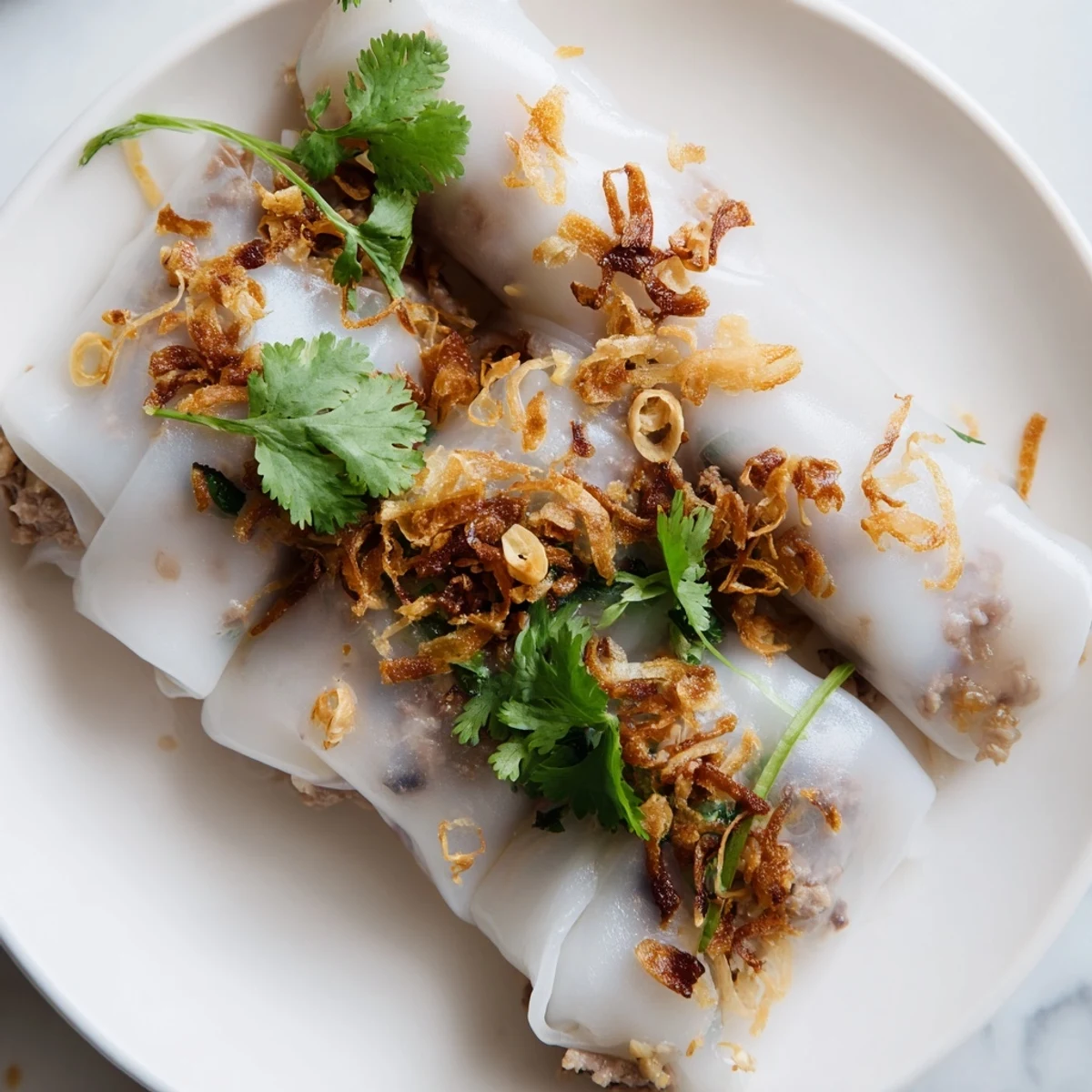 Banh Cuon plate showcasing tender rice rolls served with cucumber slices and tangy nuoc cham sauce