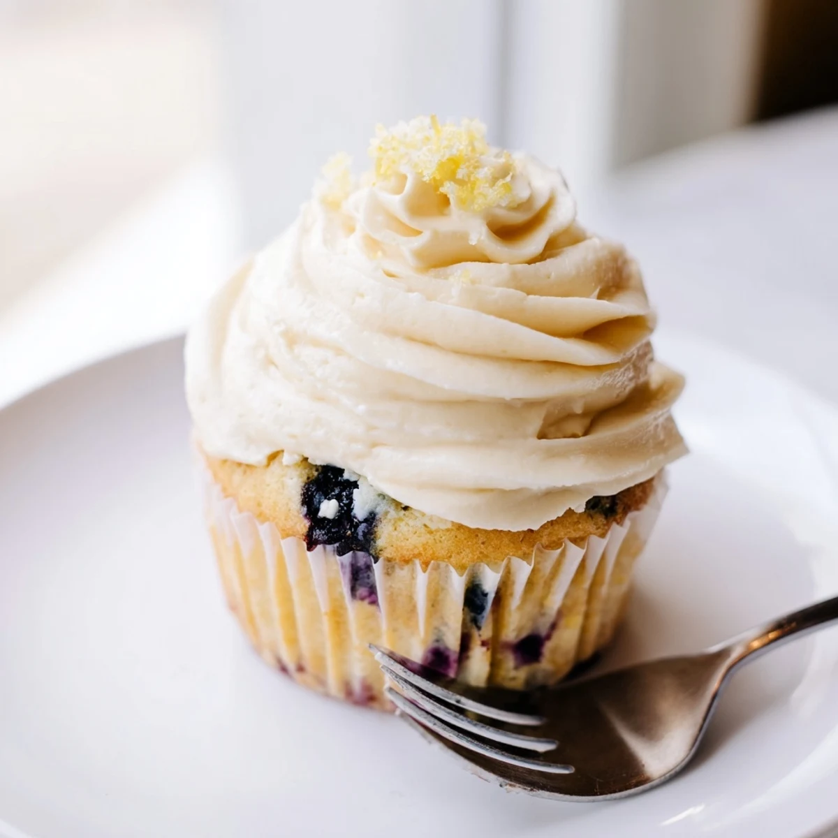 Golden lemon blueberry cupcakes topped with fluffy cream cheese frosting and fresh blueberry garnish