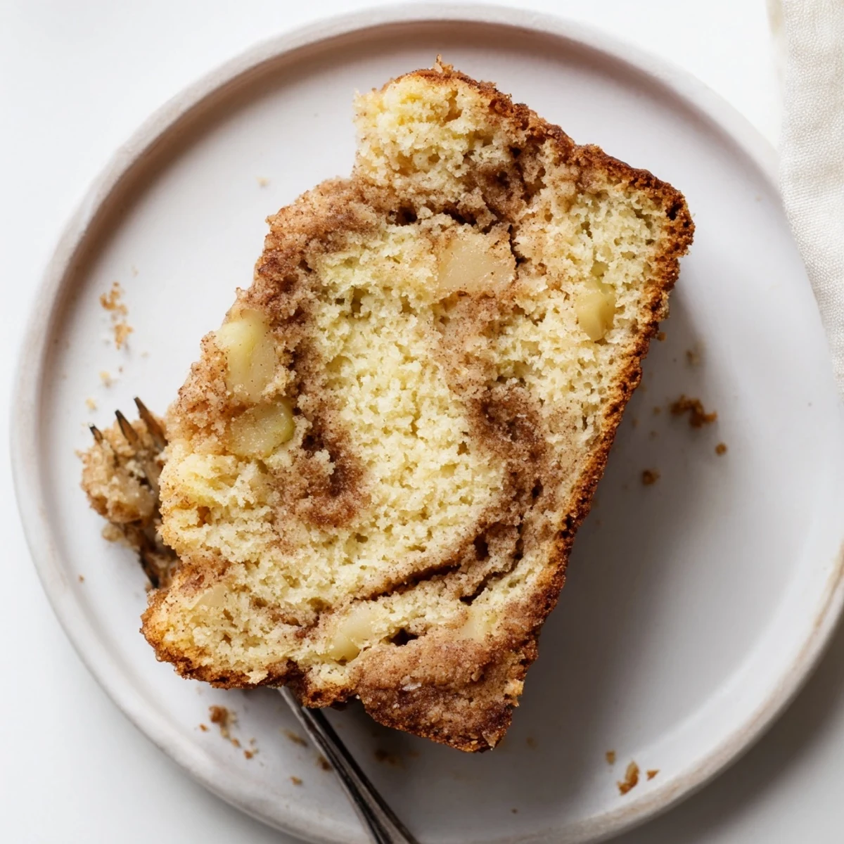 Moist homemade cinnamon apple bread sliced on a wooden board with visible apple pieces