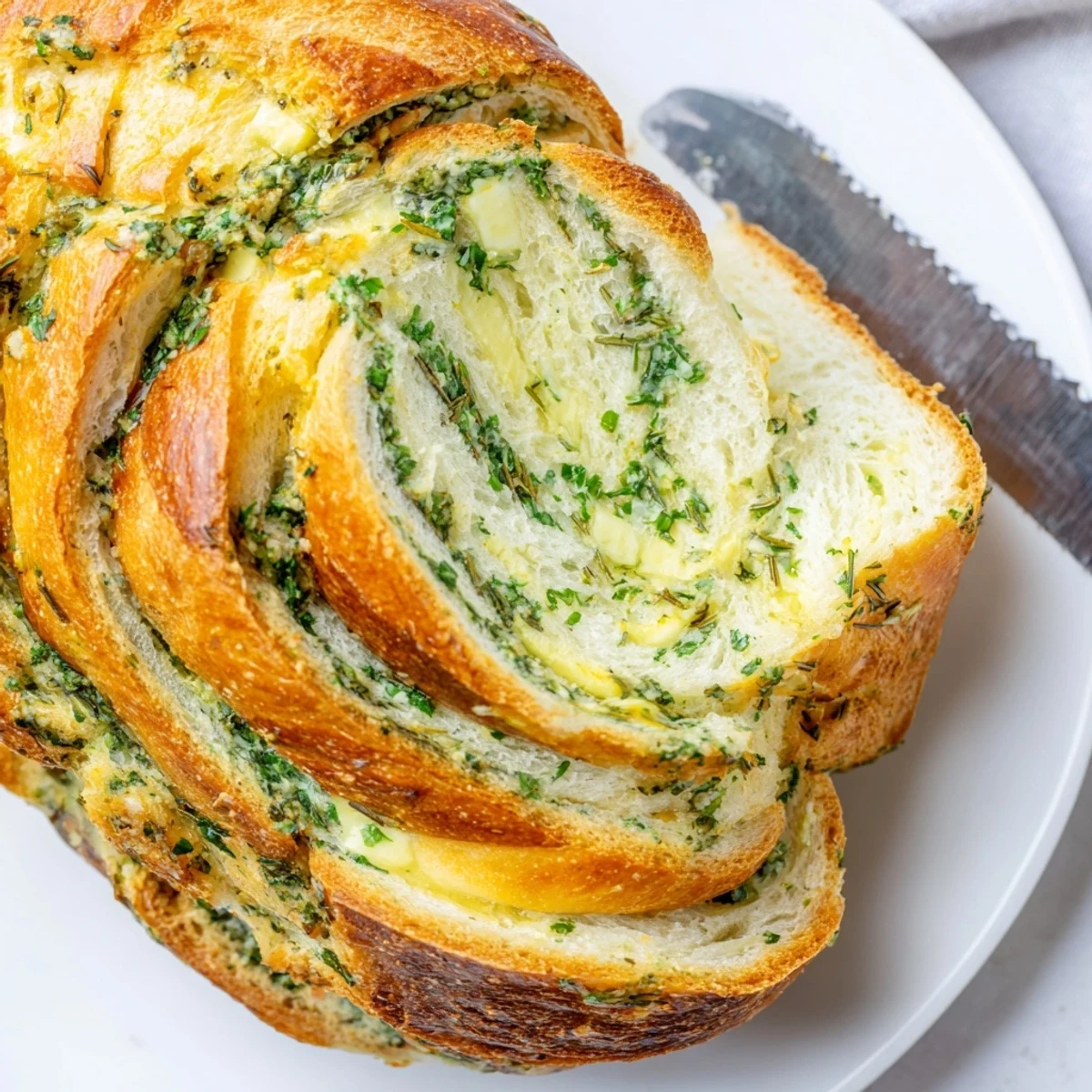 Sliced garlic and herb bread arranged on wooden board with melted butter visible on top