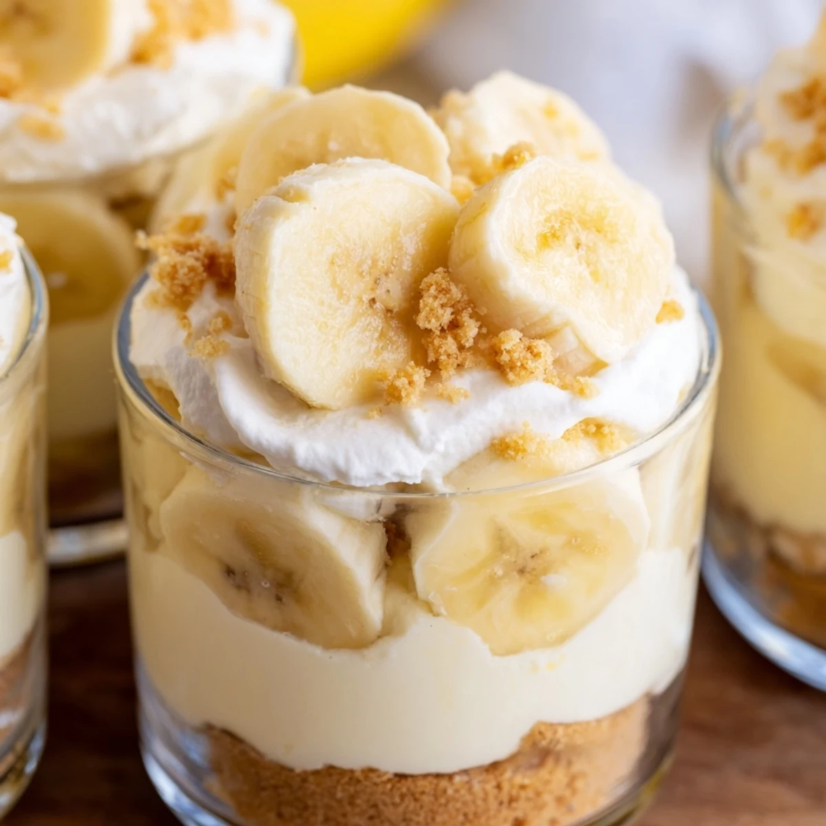 Creamy no bake banana pudding cheesecake cups layered with fresh banana slices and vanilla wafer crumbs
