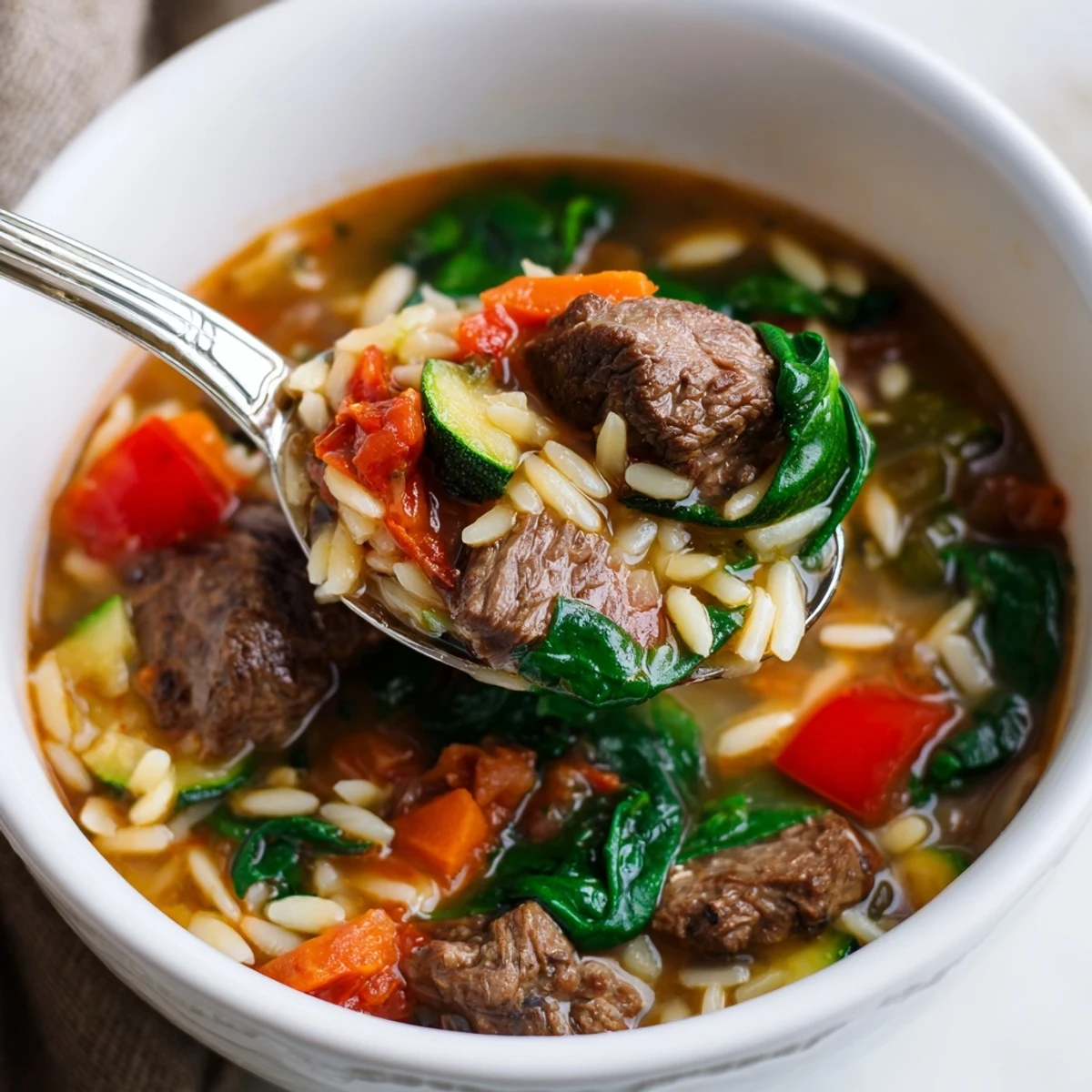 Hearty beef and orzo soup with tender vegetables in steaming savory broth