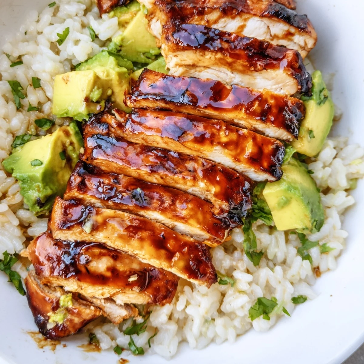 Sliced honey lime chicken resting on fluffy avocado rice with fresh cilantro garnish