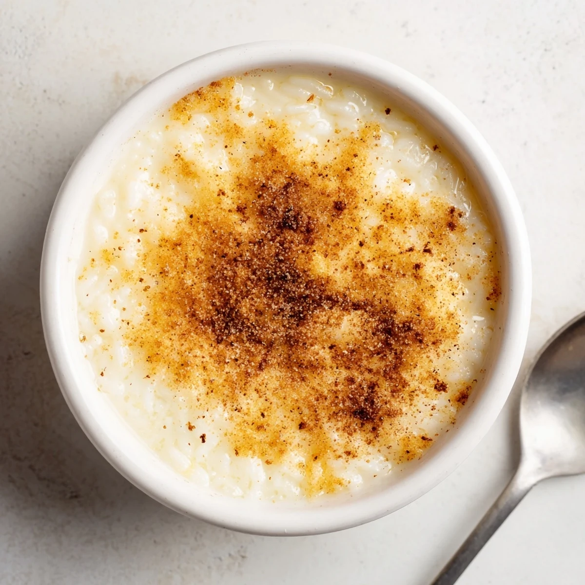 Creamy Portuguese rice custard in white ramekins with golden cinnamon-sugar topping