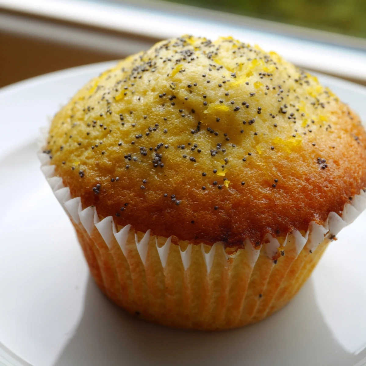 Golden lemon poppy seed muffins with domed tops resting in a lined muffin tin