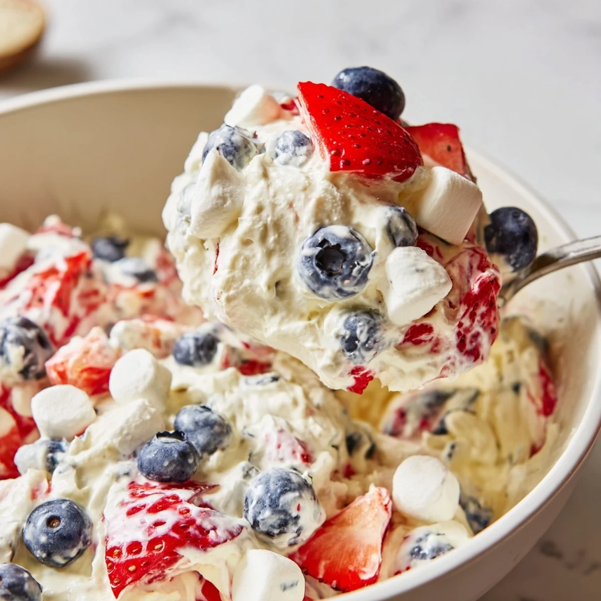 Vibrant strawberries and blueberries folded into a fluffy red white blue cheesecake salad dessert