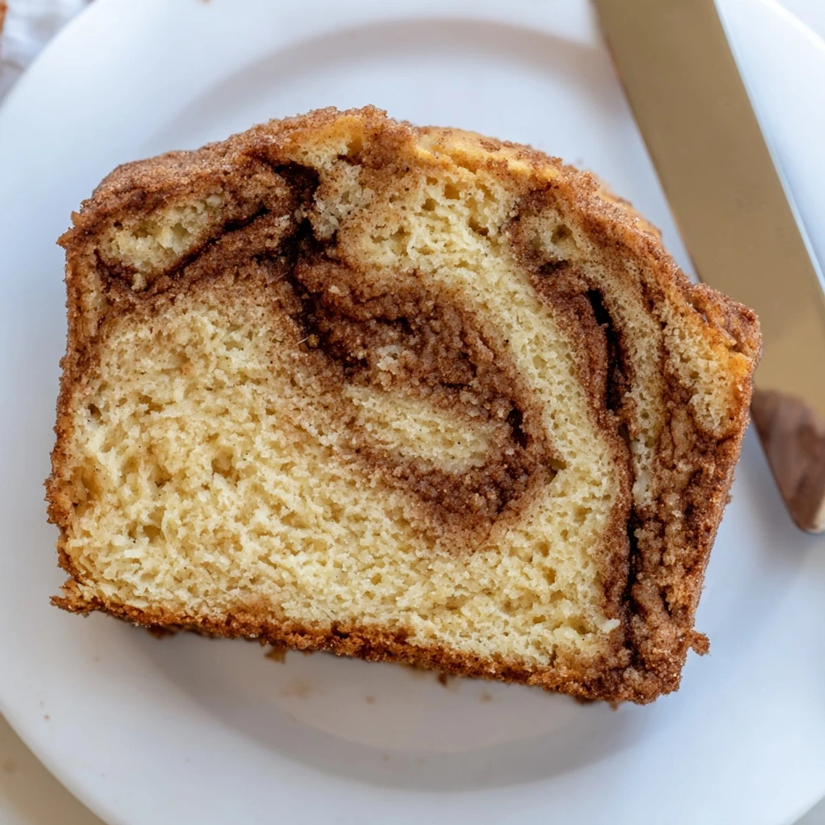 Warm slice of snickerdoodle banana bread topped with melting butter and a dusting of cinnamon