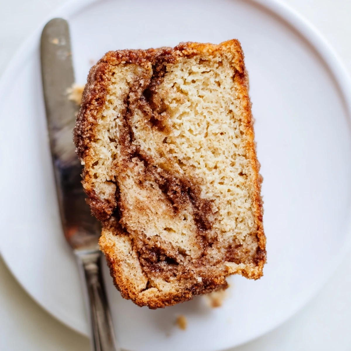Thick slice of snickerdoodle banana bread showing the marbled cinnamon-sugar layer on a white plate