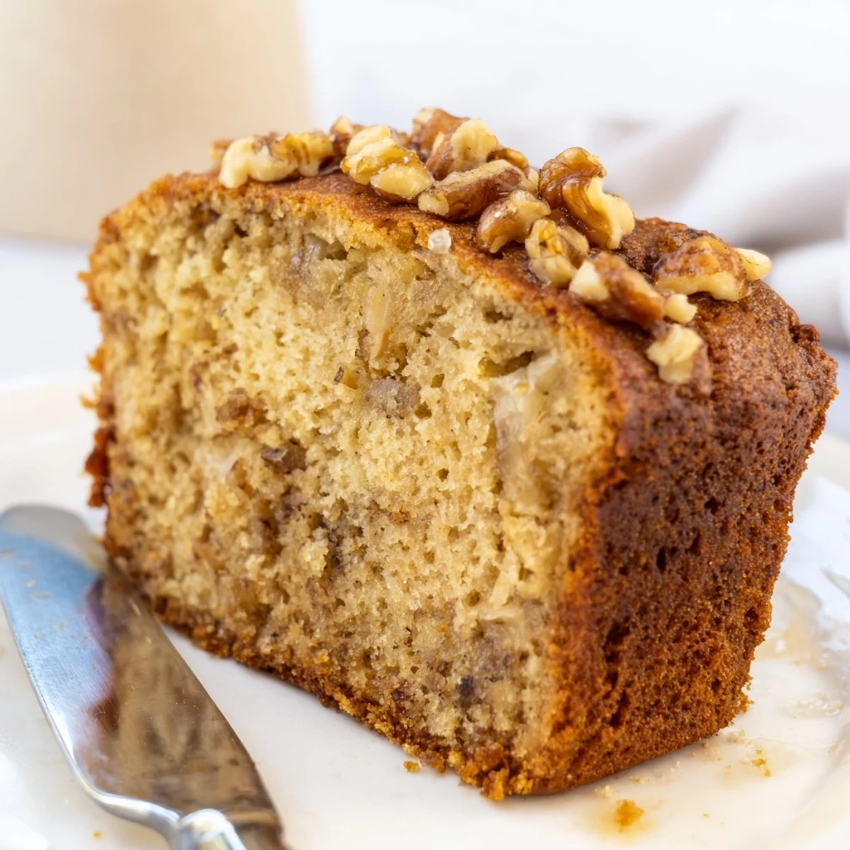Golden banana nut bread sliced on a rustic board with scattered walnuts