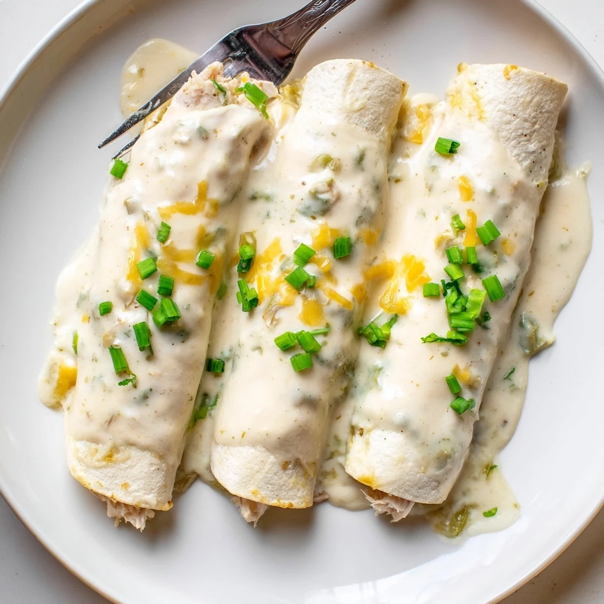 Creamy White Chicken Enchiladas bubbling with golden cheese and fresh cilantro garnish