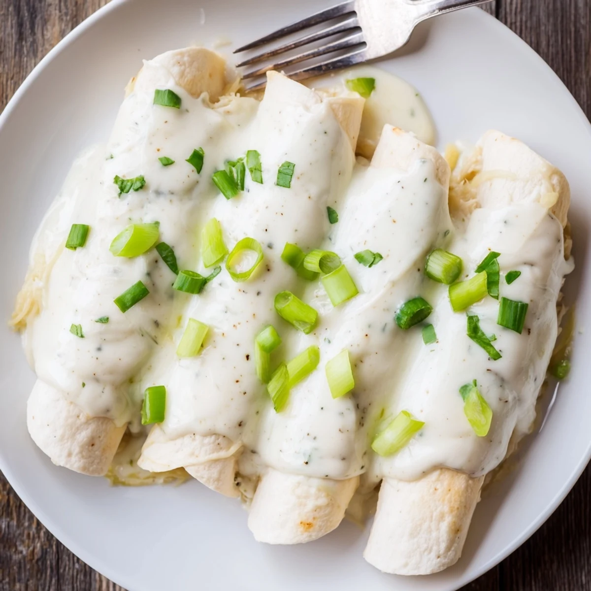 Warm Creamy White Chicken Enchiladas plated beside Spanish rice, tangy sour cream dollop
