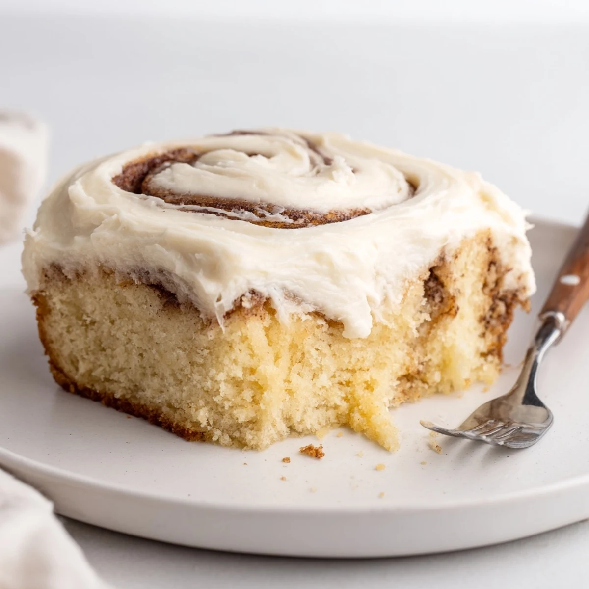 Cinnamon Roll Poke Cake with glossy cream cheese frosting and gooey cinnamon pockets