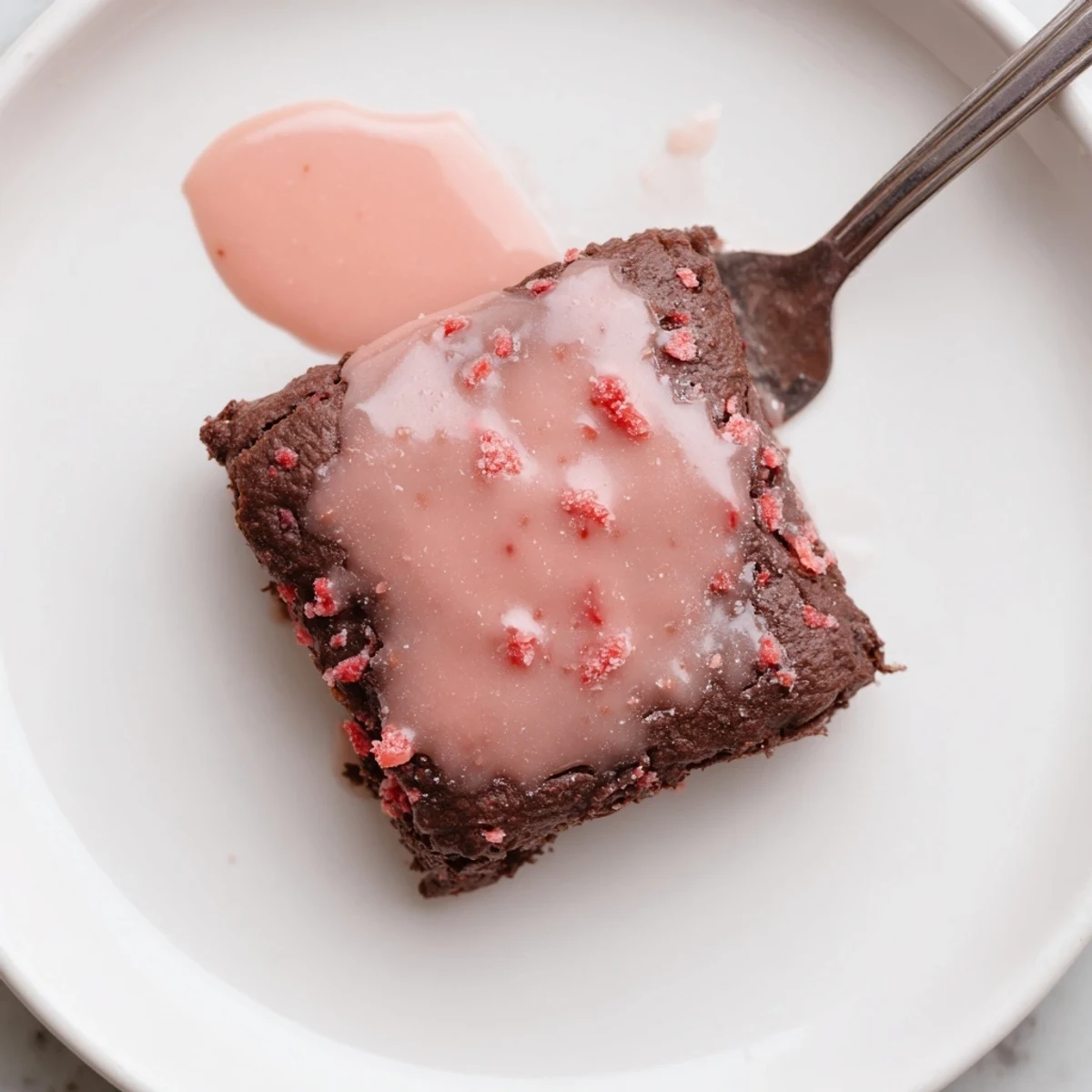 Warm strawberry brownies cut into squares, served with whipped cream and fresh strawberries.
