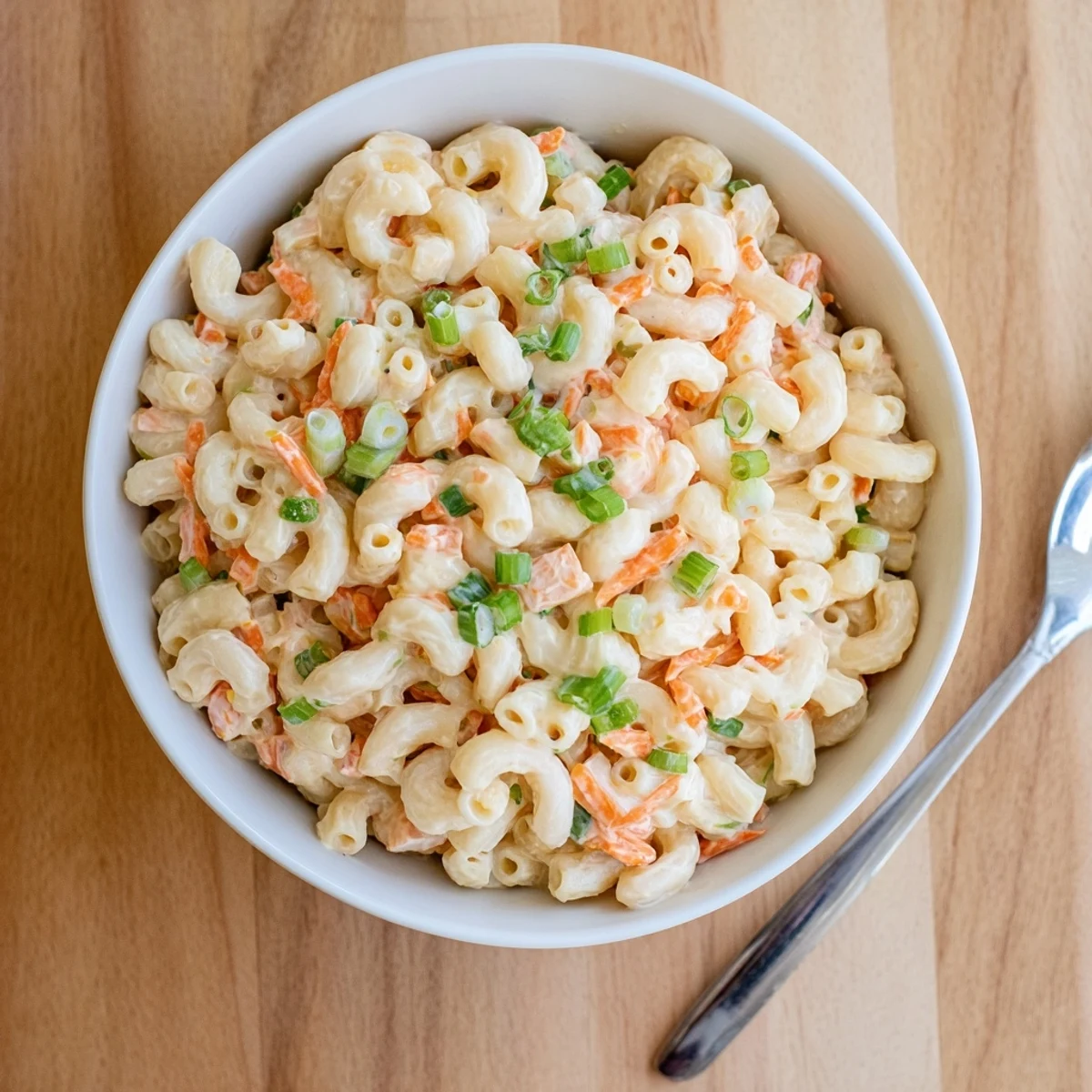 Creamy Hawaiian mac salad with grated carrots and celery in a white serving bowl