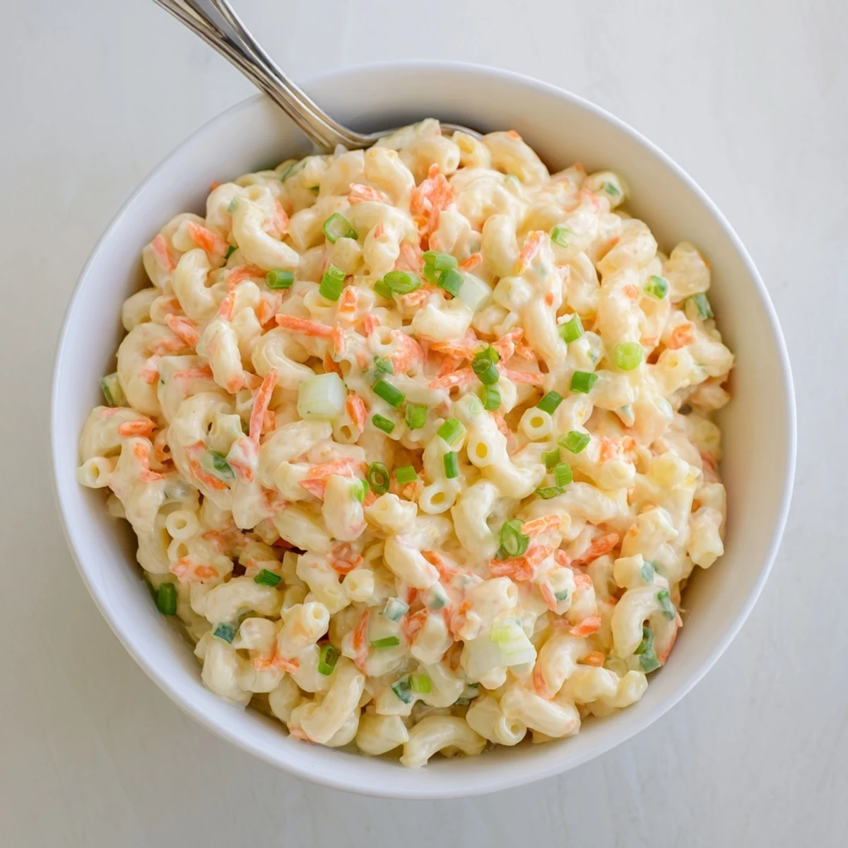 Tangy macaroni salad featuring tender pasta coated in mayonnaise dressing with green onion garnish