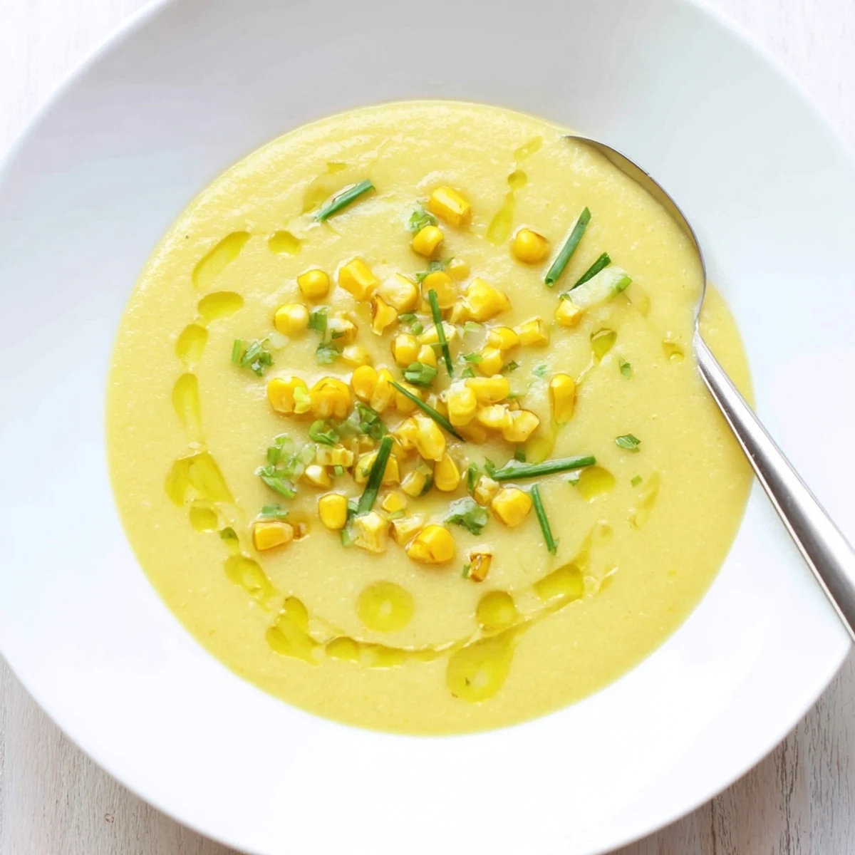 Creamy summer sweet corn gazpacho served chilled in a bowl with fresh basil garnish