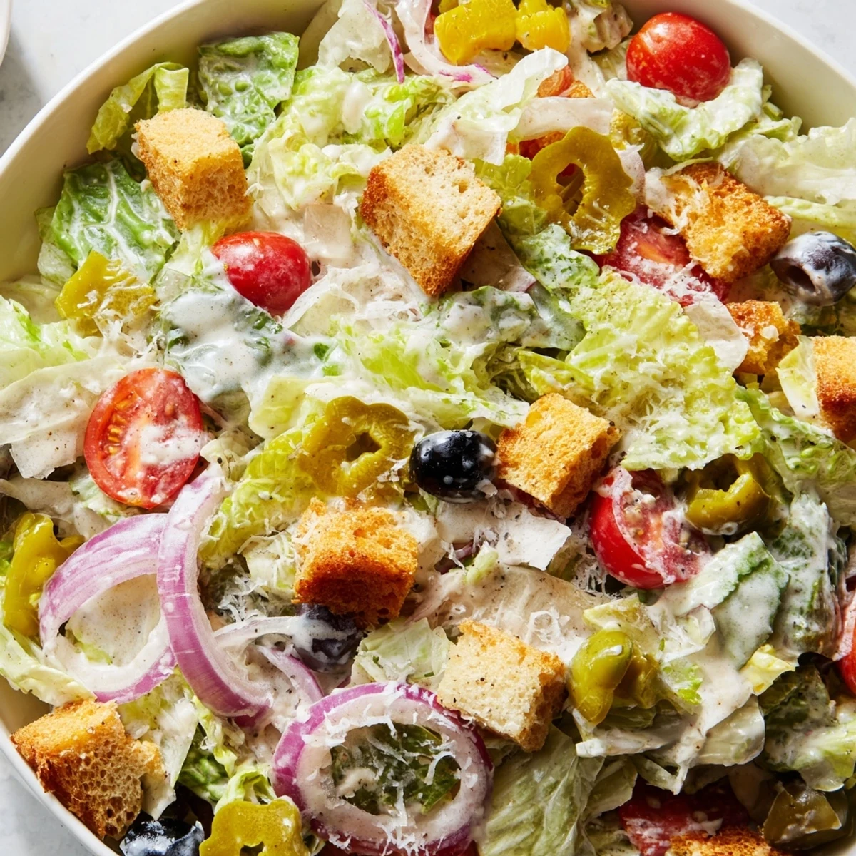 Fresh Olive Garden Salad featuring crunchy croutons, black olives, and shaved Parmesan